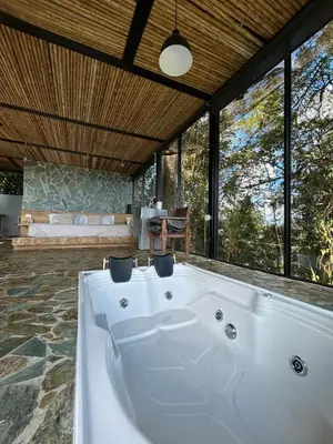 a large white bath tub in a room with windows at GLAMPING ENTRE MONTES Y CAFETALES in Santuario