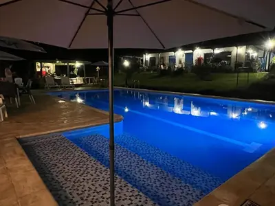 an umbrella next to a swimming pool at night at Hacienda San Francisco in Venecia