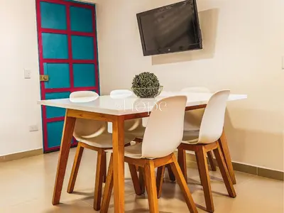 a dining room table with four chairs and a tv at Aparta Hotel Guatape Faith 101 by Hope in Guatapé