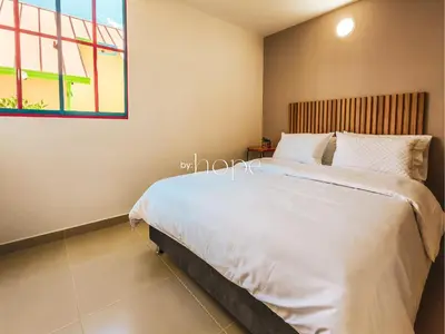 a bedroom with a large bed and a window at Aparta Hotel Guatape Faith 101 by Hope in Guatapé