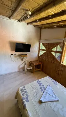a bedroom with a bed and a flat screen tv at Hostería El Sendero - Cocorná in Cocorná