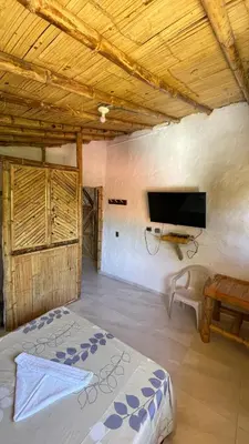 a bedroom with a bed and a flat screen tv at Hostería El Sendero - Cocorná in Cocorná