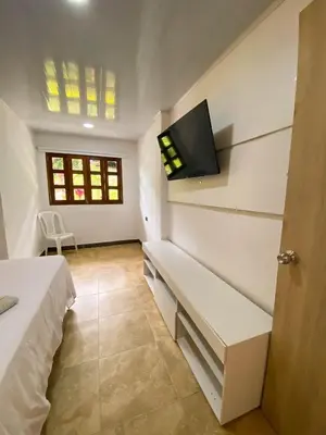 a bedroom with a bed and a tv on the wall at Hostería El Sendero - Cocorná in Cocorná
