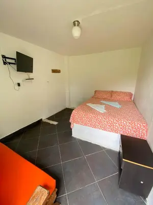 a small room with a bed and a tv at Hostería El Sendero - Cocorná in Cocorná