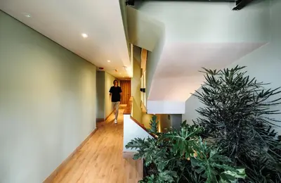 a woman walking down a hallway with plants at The Somos Central Hotel Poblado in Medellín