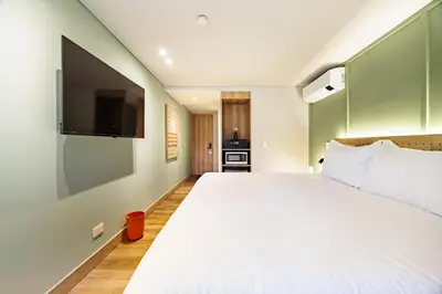 a bedroom with a large bed and a flat screen tv at The Somos Central Hotel Poblado in Medellín