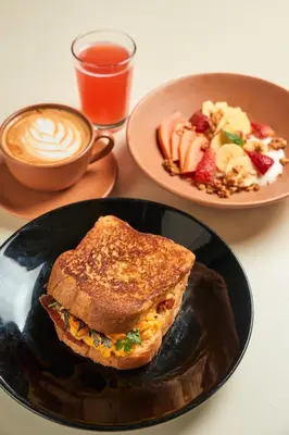 a table with a plate of breakfast food and a cup of coffee at The Somos Central Hotel Poblado in Medellín