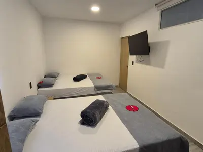 two beds in a room with a tv on the wall at Hotel Spa Laureles in Medellín