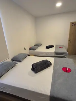 a room with three beds in a room with a door at Hotel Spa Laureles in Medellín