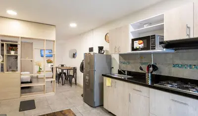 a kitchen with a refrigerator and a dining room at Tranvia 40 - Amoblados Velasquez in Medellín