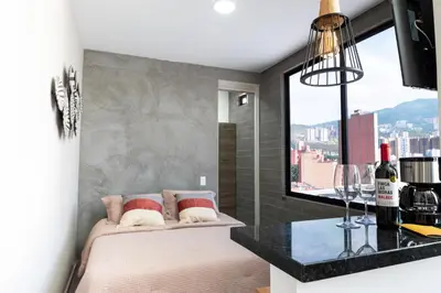 a bedroom with a bed and a large window at Cozy New Loft in Laureles / Estadio! in Medellín