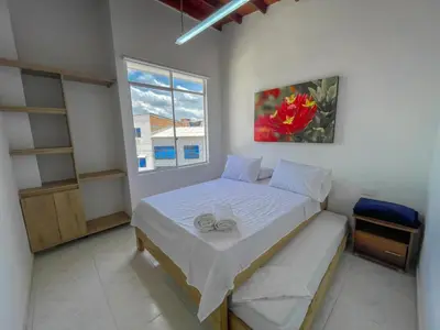 a small bedroom with a bed and a window at Apartahotel Rosedal in Doradal