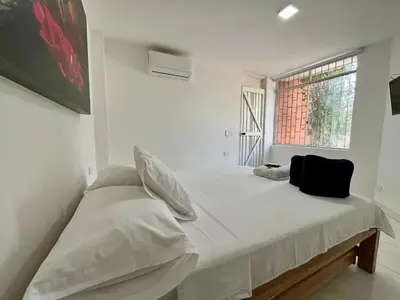 a white bedroom with a bed and a window at Apartahotel Rosedal in Doradal