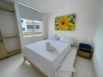 a small bedroom with a white bed with a table at Apartahotel Rosedal in Doradal