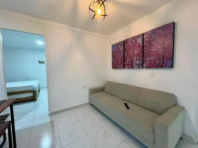 a living room with a couch and a painting on the wall at Apartahotel Rosedal in Doradal