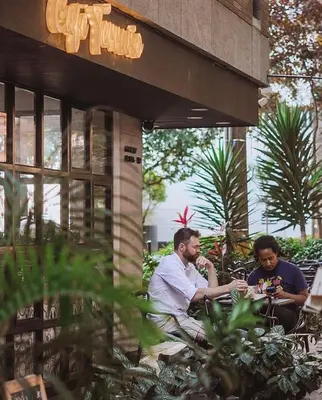 two men sitting at a table outside of a building at Apartamento Lauret en Laureles in Medellín