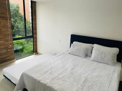 a bedroom with a white bed with a large window at Apartamento Lauret en Laureles in Medellín