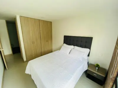 a bedroom with a white bed and a wooden cabinet at Apartamento Lauret en Laureles in Medellín