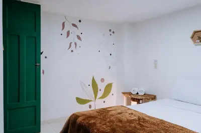 a bedroom with a bed and a green door at Origen Hostel Jardín in Jardin
