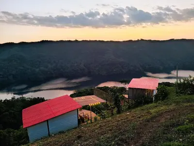 two buildings with red roofs on a hill with a view at COCOZNA Glamping in Norcasia