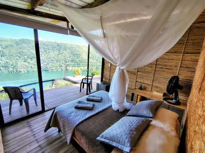 a bedroom with a bed with a view of the water at COCOZNA Glamping in Norcasia
