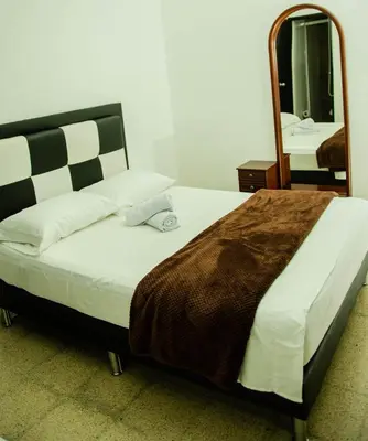 a bedroom with a large bed with a mirror at CASA HOTEL LOS ARBOLES in Bello