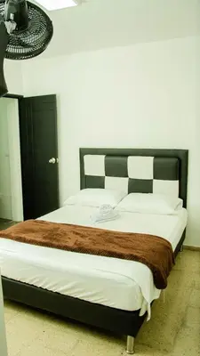 a bedroom with a large bed with white sheets and brown blanket at CASA HOTEL LOS ARBOLES in Bello