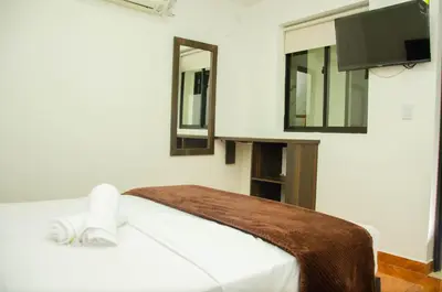 a bedroom with a bed with a tv and mirrors at CASA HOTEL LOS ARBOLES in Bello