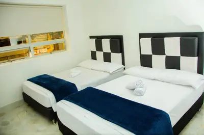 two twin beds in a room with two windows at CASA HOTEL LOS ARBOLES in Bello