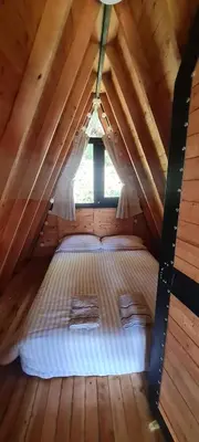 a bed in a wooden room with a roof at Cabaña Starka & Jacuzzi in Marinilla