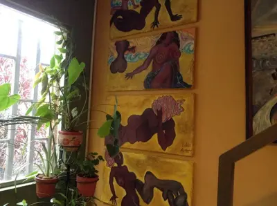a wall with paintings of mermaids and potted plants at Apartamento-Galería de arte Cielo y Tierra in Medellín