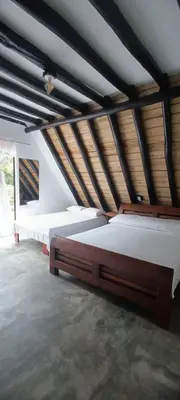 two beds in a large room with wooden ceilings at Isla Escondida Maceo Finca Hotel y Restaurante in Yolombó