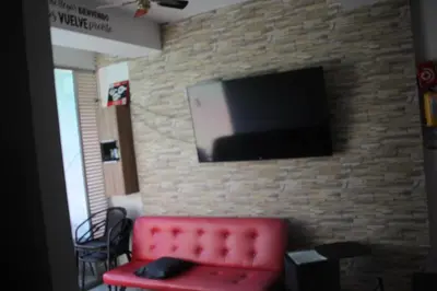 a living room with a red couch and a television on a brick wall at Hakuna Matata in San Jerónimo