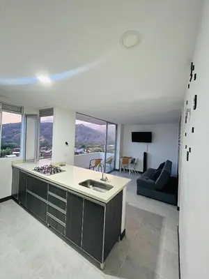 a kitchen with a stove and a living room at ¡Vista Increíble Apartamento Tamarindo! in Santa Fe de Antioquia
