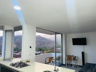 a kitchen with a stove and a balcony with mountains at ¡Vista Increíble Apartamento Tamarindo! in Santa Fe de Antioquia