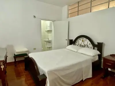 a bedroom with a white bed and a chair and a window at Casa Laura in Medellín