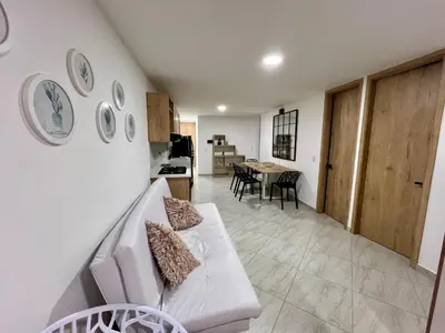 a living room with a white couch and a table at Apto cerca Malecón, Plaza Principal, Plazoleta Zocalos, a 8 min de la Piedra del Peñol, GRATIS PARQUEADERO!!! in Guatapé