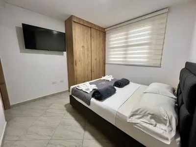 a bedroom with a bed and a flat screen tv at Apto cerca Malecón, Plaza Principal, Plazoleta Zocalos, a 8 min de la Piedra del Peñol, GRATIS PARQUEADERO!!! in Guatapé