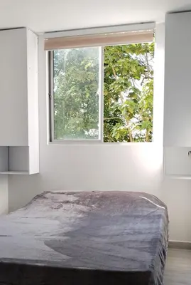 a bedroom with a large window in a white room at Semi-loft Manizales Colombia in Manizales