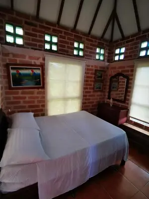 a bedroom with a white bed in a brick wall at Finca con forma de castillo y piscina en Sopetrán in Sopetran