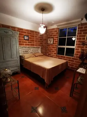 a bedroom with a bed and a brick wall at Finca con forma de castillo y piscina en Sopetrán in Sopetran