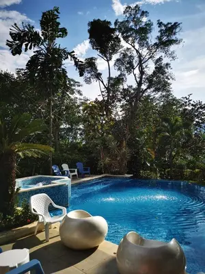 a swimming pool with two chairs and a table at Finca con forma de castillo y piscina en Sopetrán in Sopetran