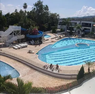 a large swimming pool in a resort with a slide at Apartasol Ciudadela Santafe in Santa Fe de Antioquia