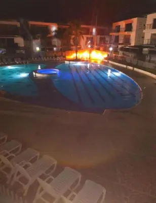 a swimming pool at night with white chairs around it at Apartasol Ciudadela Santafe in Santa Fe de Antioquia