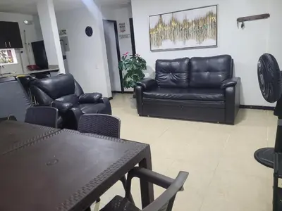 a living room with black leather furniture and a table at Apartasol Ciudadela Santafe in Santa Fe de Antioquia