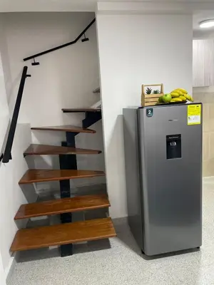 a kitchen with a refrigerator and wooden stairs at loft cerca a laureles, WIFI, cerca metro y GUARDA EQUIPAJE GRATIS!! in Medellín