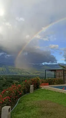 a rainbow in the sky over a garden with a pool at Piscina-gran vista-clima cálido y pueblo histórico in Santa Fe de Antioquia