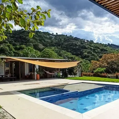 a house with a swimming pool with a tan umbrella at Piscina-gran vista-clima cálido y pueblo histórico in Santa Fe de Antioquia