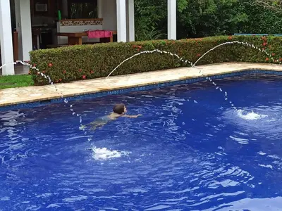 a person swimming in a pool with a water hose at Piscina-jacuzzi-calma-comodidad-Villa Old Havana in Santa Fe de Antioquia
