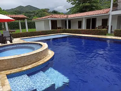 a swimming pool with blue water in front of a house at Piscina-jacuzzi-calma-comodidad-Villa Old Havana in Santa Fe de Antioquia